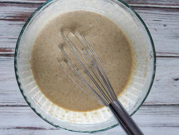 This image is to demonstrate step two of recipe of adding the milk. Images is mixing bowl with whisk and batter.