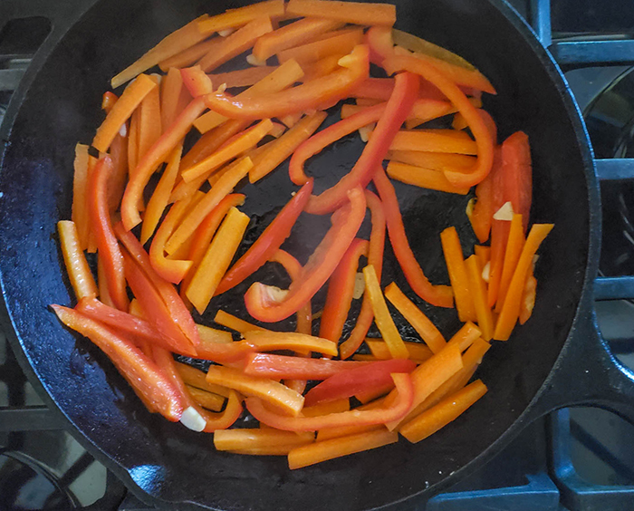 peppers, garlic and onions in a pan on the stove