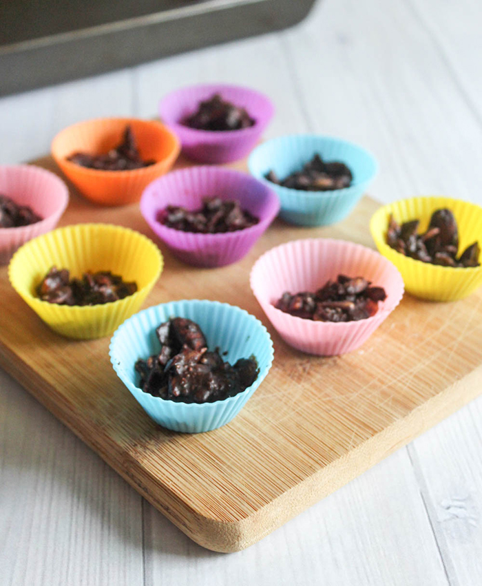 Dark chocolate almond clusters in silicone cups on a cutting board