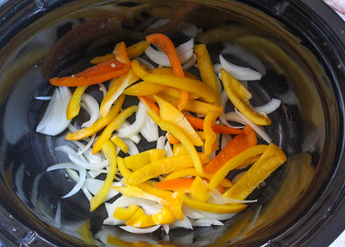 sliced peppers and onions in a slow cooker bowl