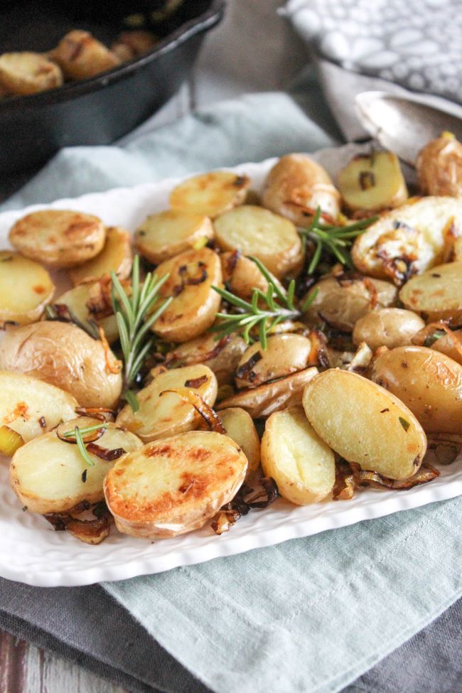 roasted baby potatoes on a plate with rosemary and leeks 