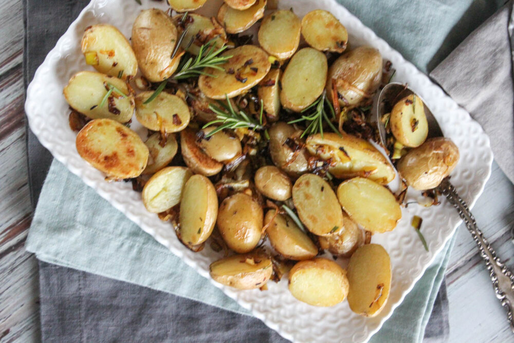 an overhead view of roasted baby potatoes on a platter with a spoon