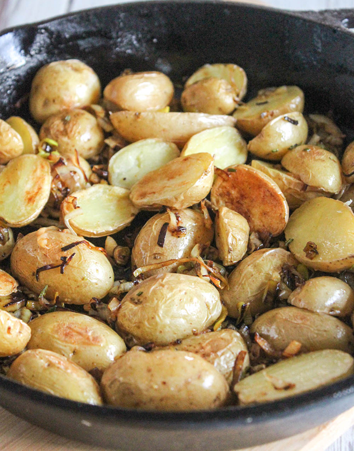 a close up of the potatoes in a skillet with the caramelized leeks 