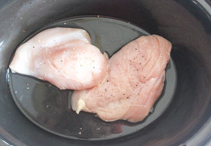 a picture of two boneless chicken breasts in a crockpot