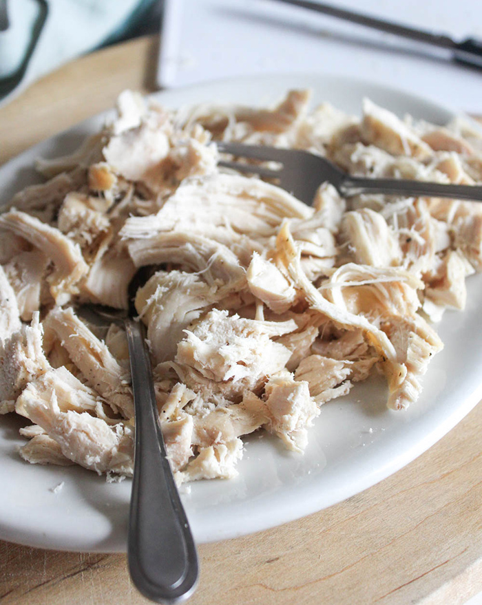 shredded chicken on a white plate with two forks