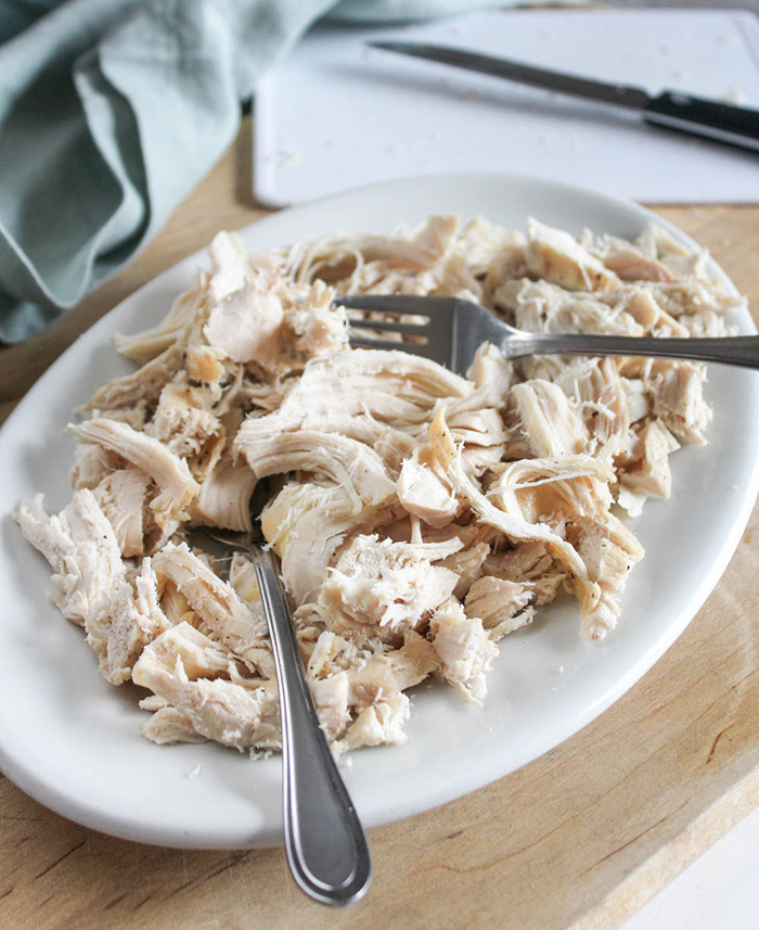 shreddded chicken on a plate with 2 forks