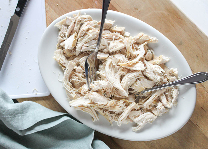 an overhead view of cooked shredded chicken on a plate with two forks