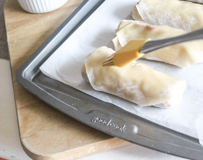 a pastry brush brushing oil onto an egg roll