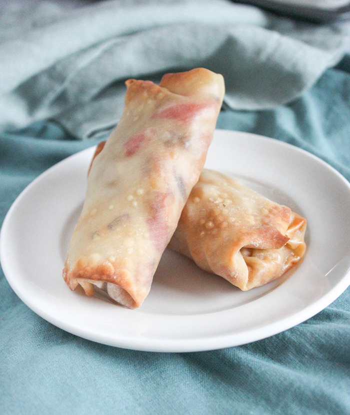 two egg rolls stacked up on a white plate