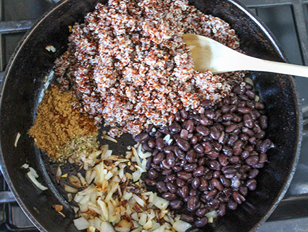 quinoa, beans, onions and seasoning in a pan 