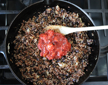 tomatoes, onions, on top of quinoa and beans in a pan 