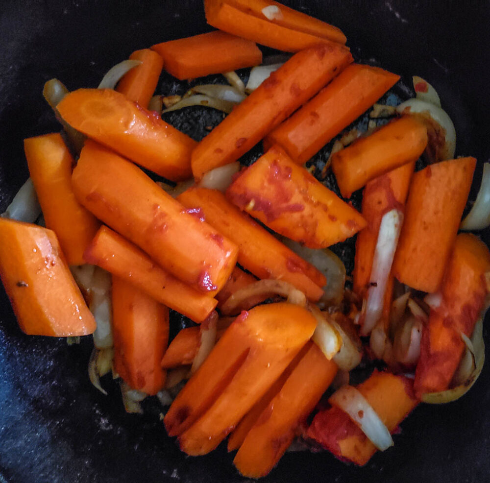carrots cooking in a skillet with tomato paste