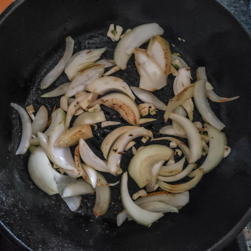 a view of onions cooking in a skillet