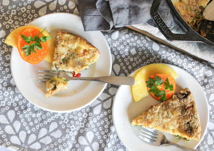 Overhead view of two breakfast pie slices on a white plates with sliced fresh fruit