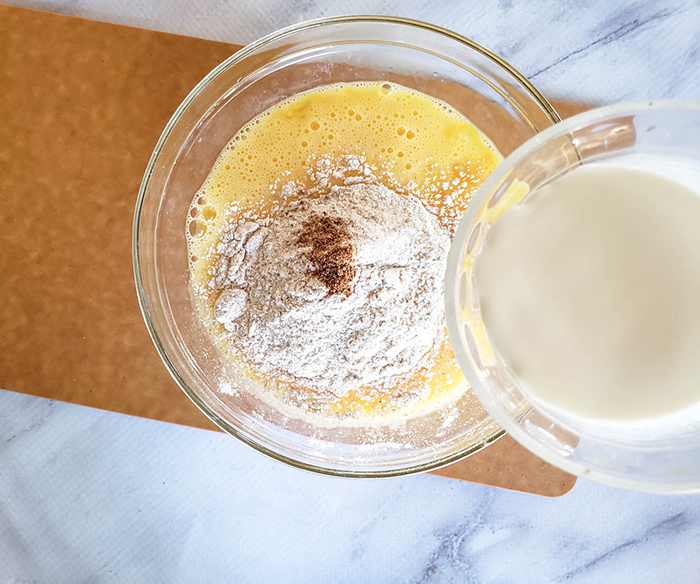 milk pouring into a mixture of eggs and flour