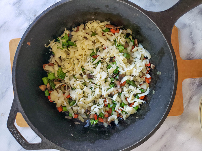 vegetables covered with shredded cheese in a skillet