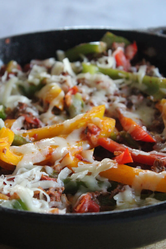 a close up picture of a pan of deconstructed stuffed peppers covered in cheddar cheese
