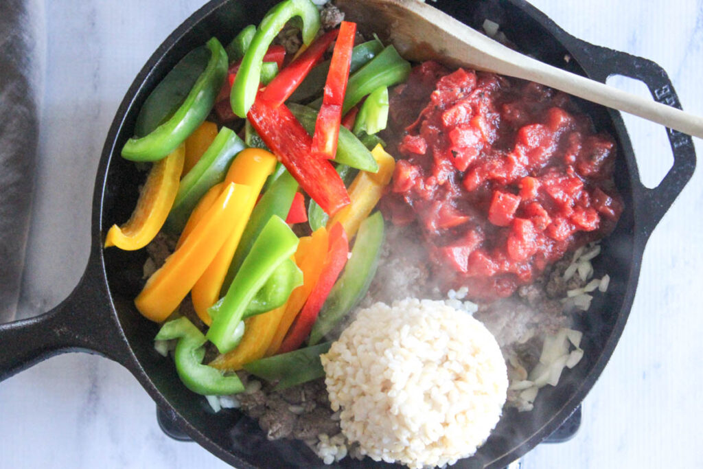 Process step 3: cooked brown beef in a pan with rice, peppers and tomatoes