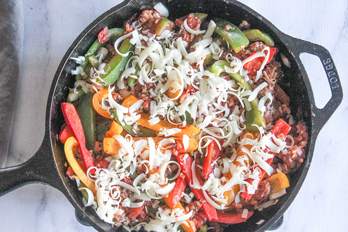 Process Step 5 deconstructed peppers in a skillet with shredded cheese on top