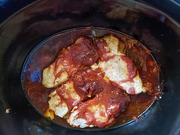 boneless pork chops in a slow cooker cooked with sauce on top