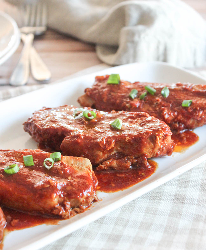 a picture of cooked honey garlic pork chops on a platter covered in sauce