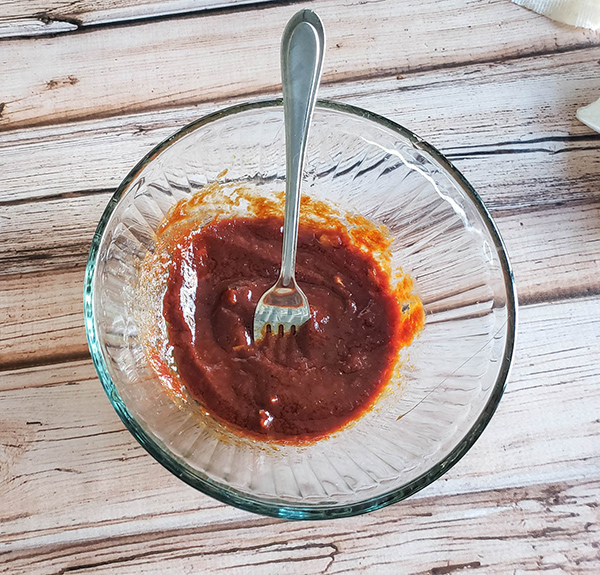 a bowl of bbq sauce with a fork in it.