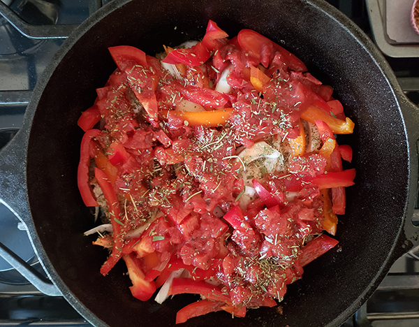 pork chops in a skillet topped with tomatoes and seasoning