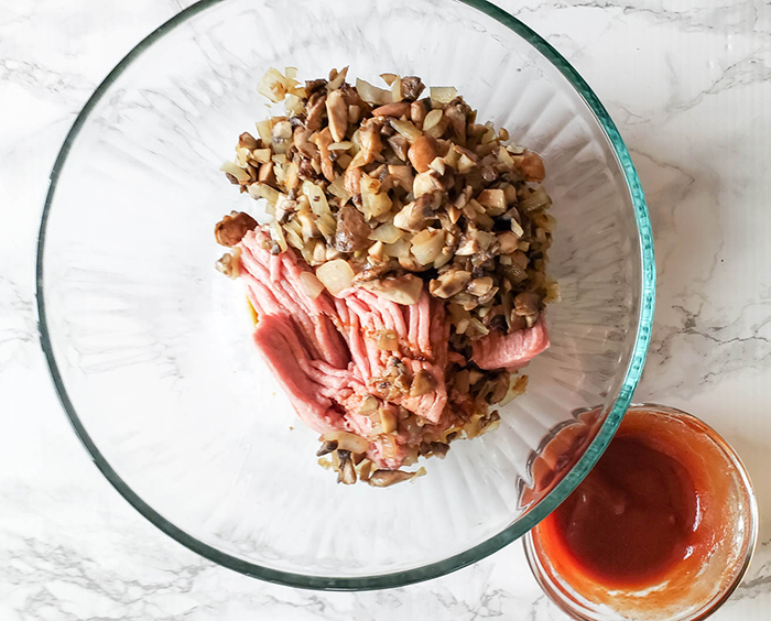 Turkey with onions and mushrooms in a bowl before being mixed together