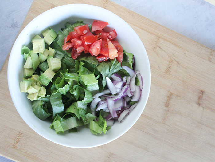 lettuce tomatoes, onions, avocado in a bowl