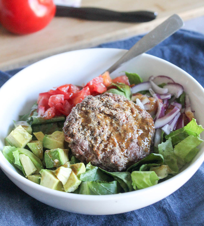 burger in a bowl on top of lettuce with a fork