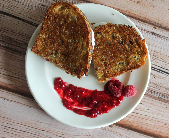 an overhead shot of grilled brie cheese with raspberry sauce on the side