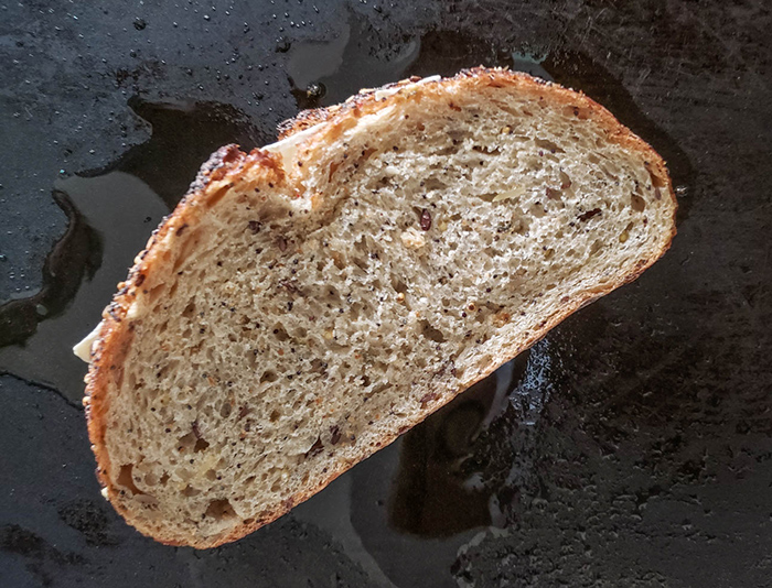 grilled cheese sandwich cooking on a griddle before being flipped