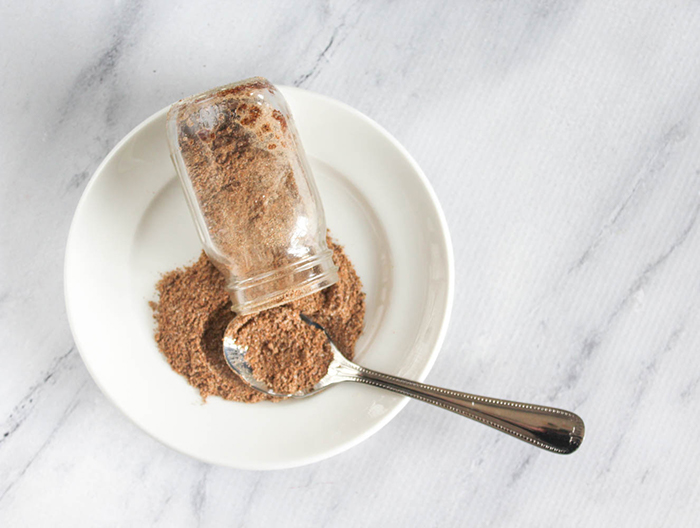 a jar spilling the taco seasoning with a spoon