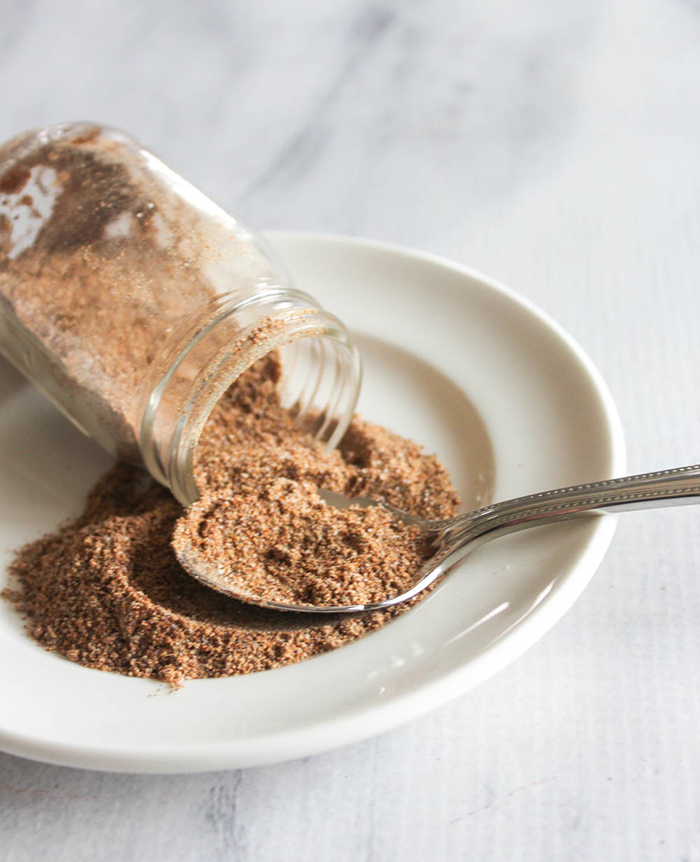 Taco seasoning mix spilling out of a jar onto a plate