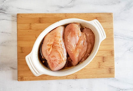 boneless chicken breasts in a white dish with balsamic marinade