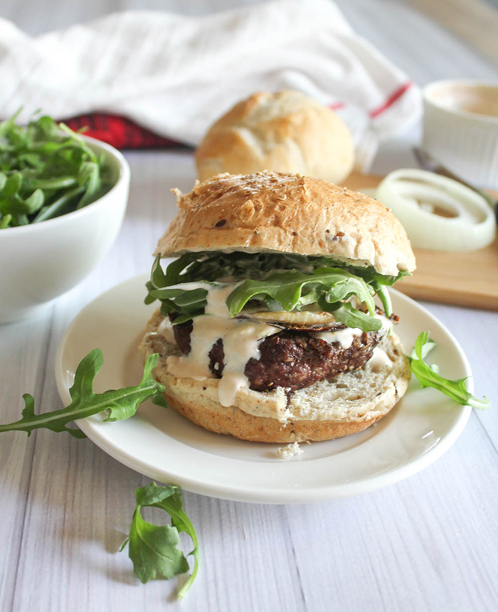 a burger in a roll with sauce on a plate