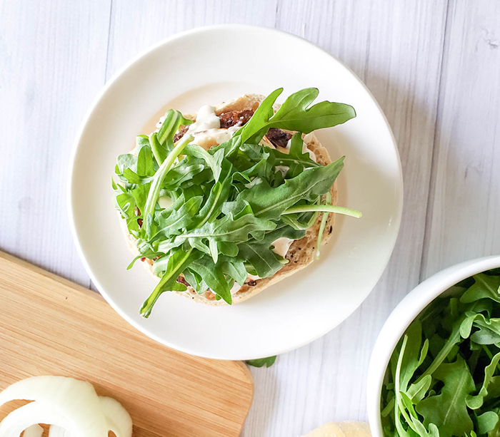 grilled onion burger on a plate covered with arugula