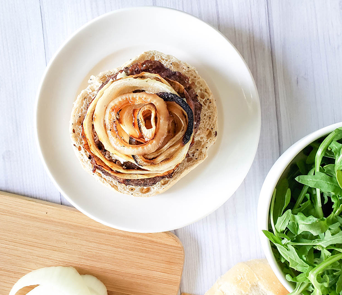 a burger on a plate with grilled onions