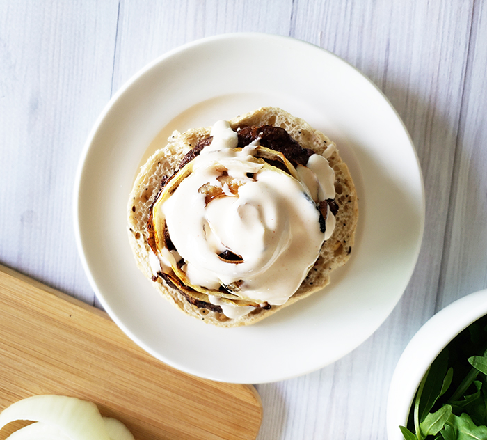 a burger on a plate covered in yogurt sauce