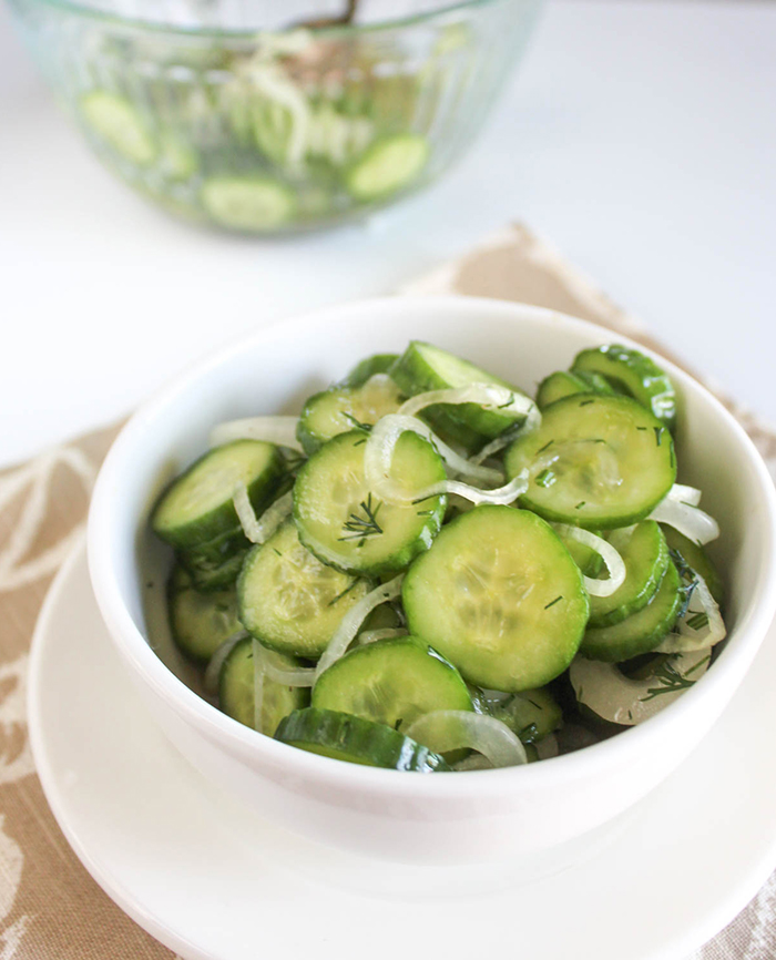 A close up of cucumbers and onions in vinegar in a bowl.