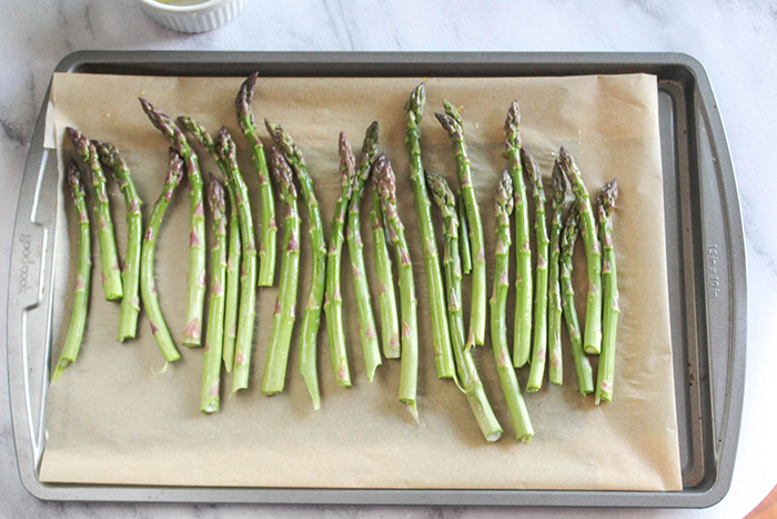 raw asparagus on a baking sheet lined with parchment paper