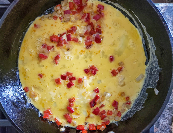 scrambled eggs in a pan with peppers and onions
