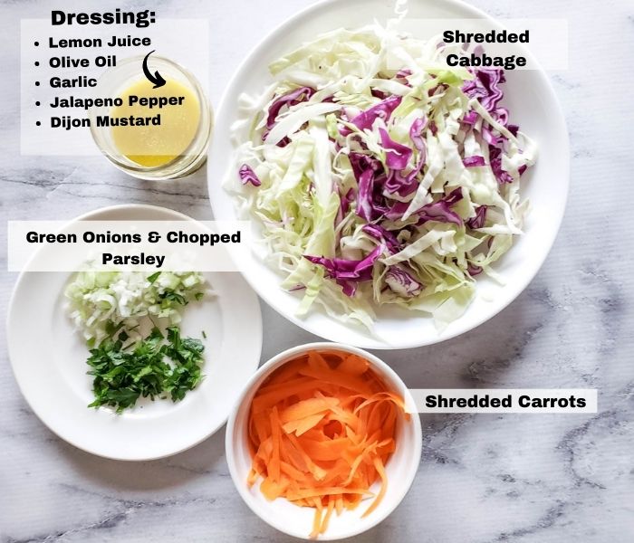 an overhead view of the ingredients: chopped onions & parsley, Shredded carrots, shredded cabbage, dressing