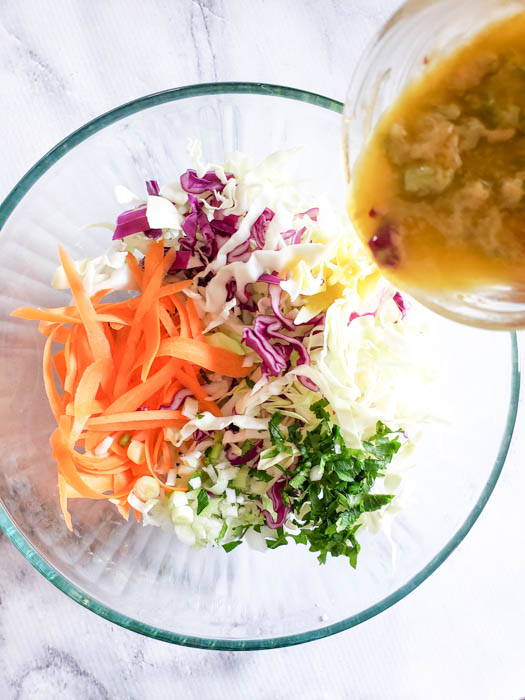 A view of the dressing being poured into the bowl with the vegetables.