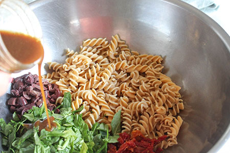 dressing pouring over the pasta salad