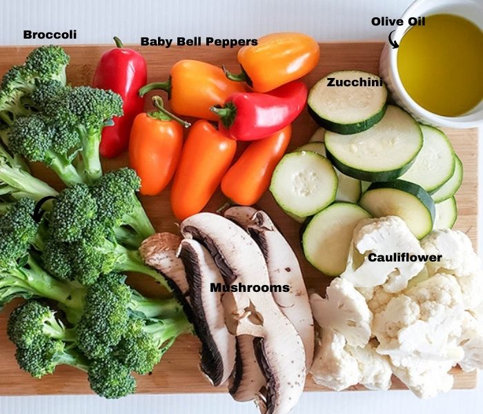 an overhead view of raw vegetables: broccoli, cauliflower, mushrooms, peppers zucchini and olive oil