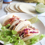 three korean tacos on a plate with lettuce