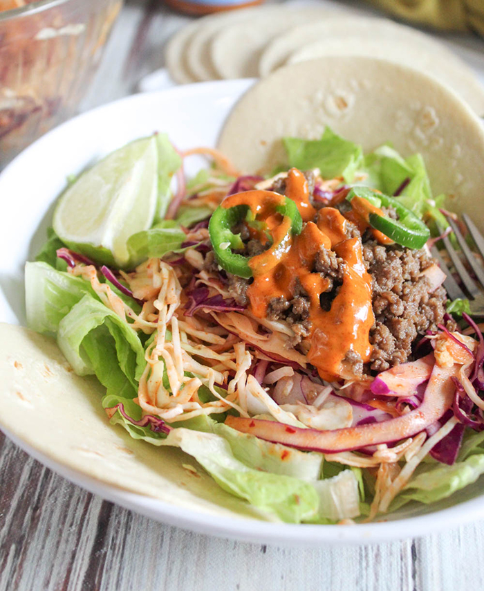 beef tacos in a bowl with lettuce and tortillas