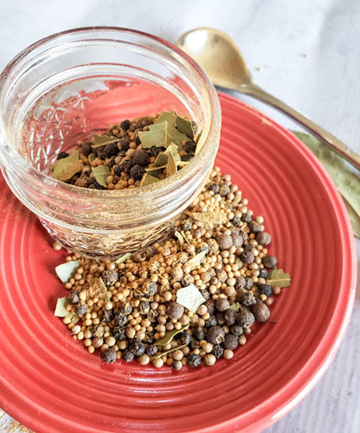 Pickle spice on a plate with a half filled jar next to it