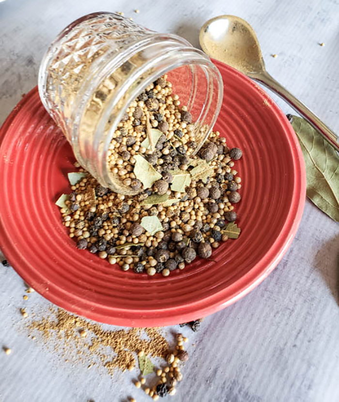 photo of pickle spice pouring out of a jar onto a red plate